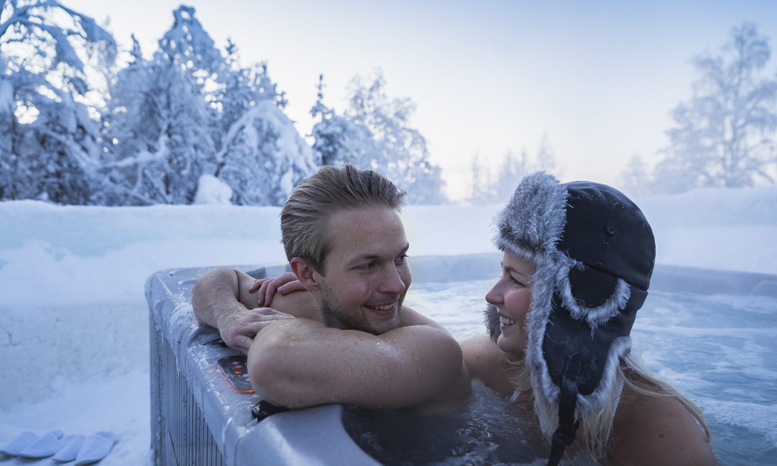 Pariskunta ulkoporealtaassa lumen ympäröimänä