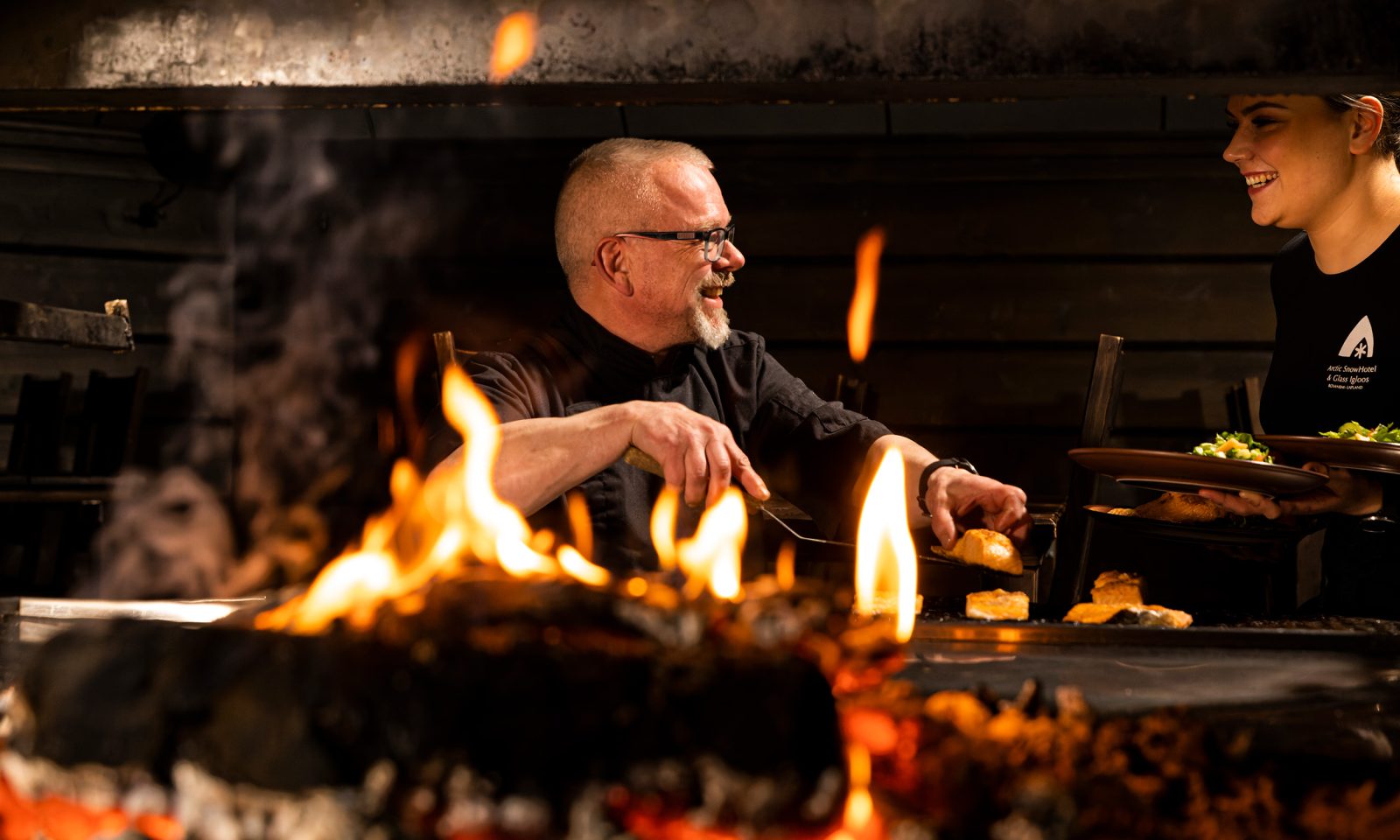 Kokki valmistaa loimutettua lohta avotulella Kotaravintolassa