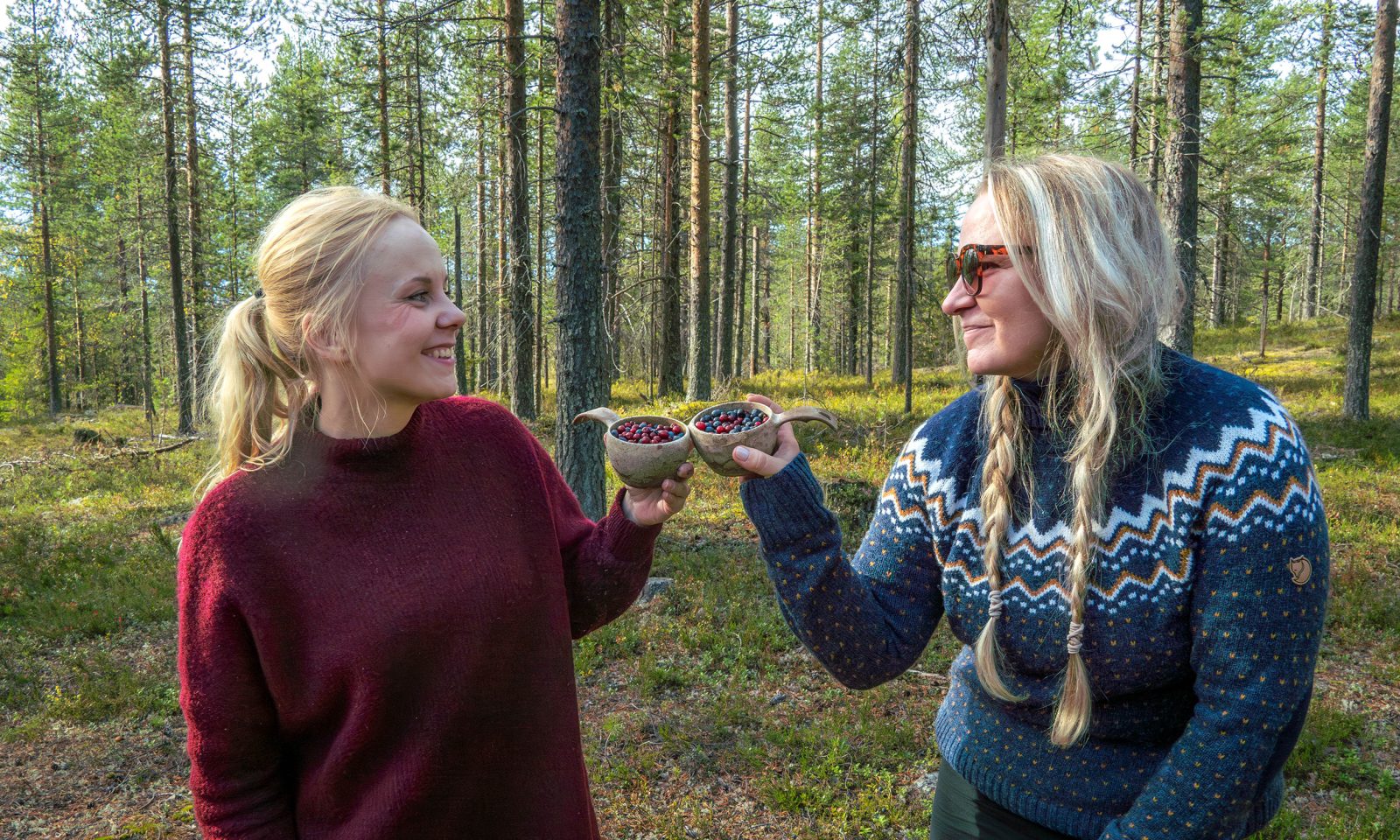 Kaksi vierailijaa kippistää kuksilla, jotka ovat täynnä marjoja