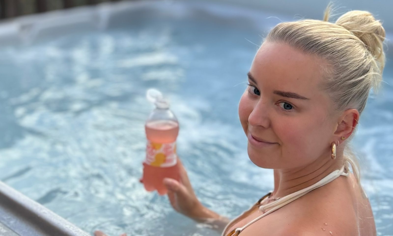 Nainen nautiskelee juomasta ulkoporealtaassa