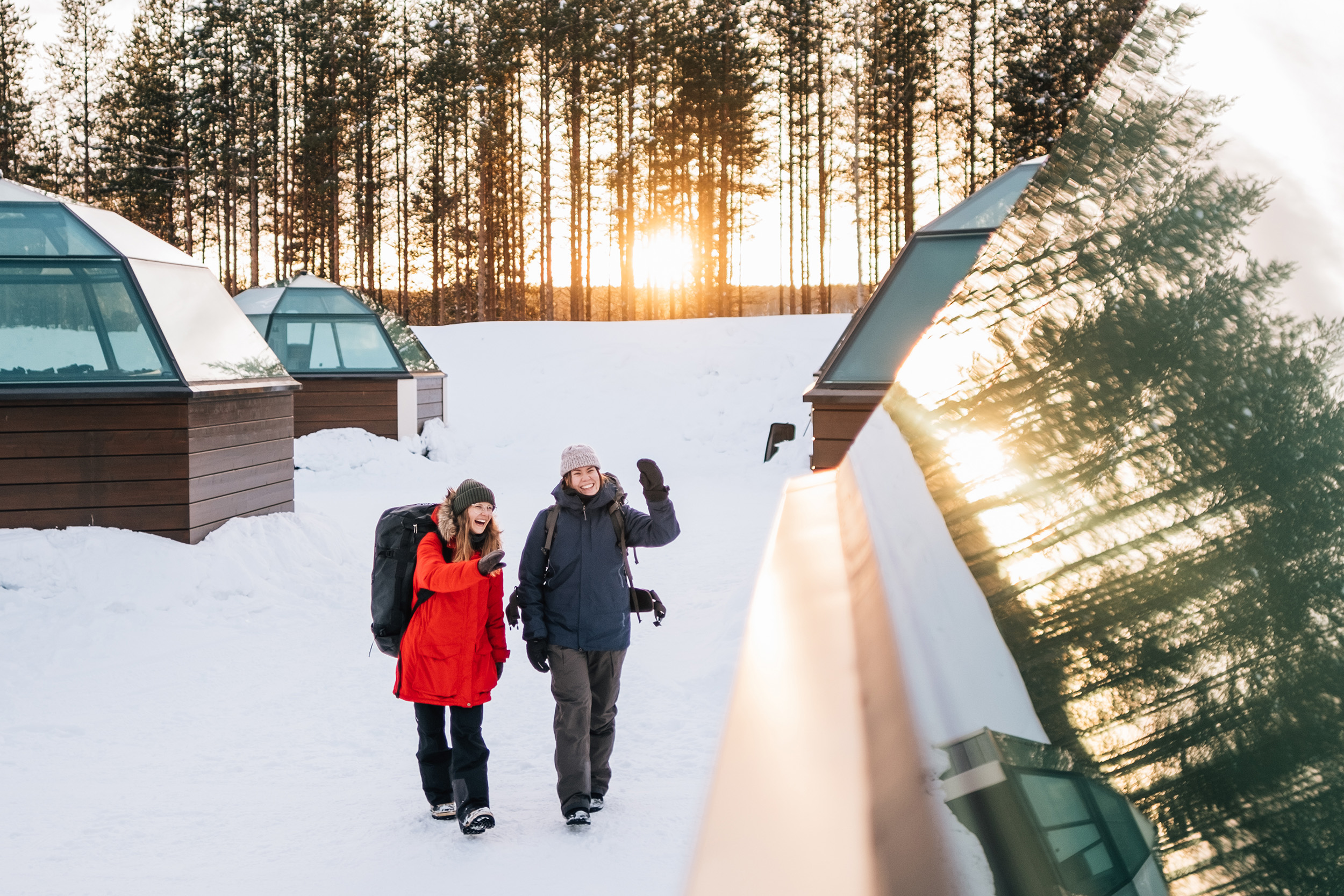 Two person outside of Glass igloos in winter