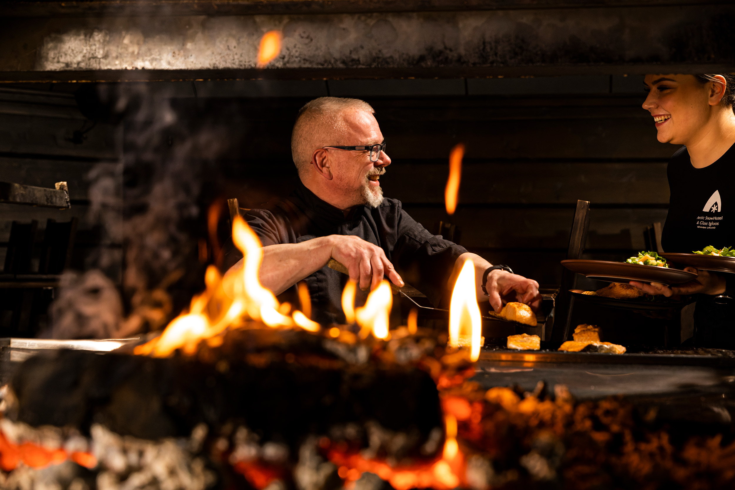 A cook preparing the food behind fire