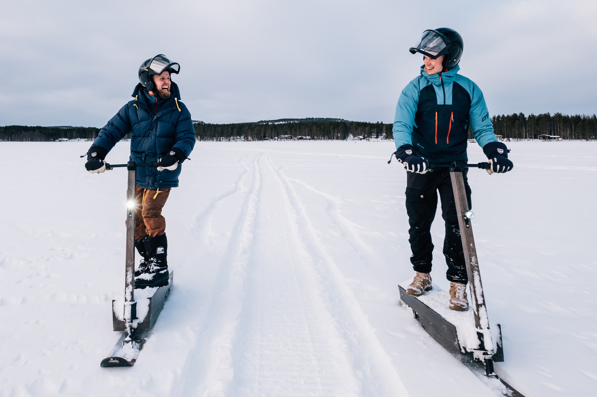 Kaksi miestä lumiskootterisafarilla