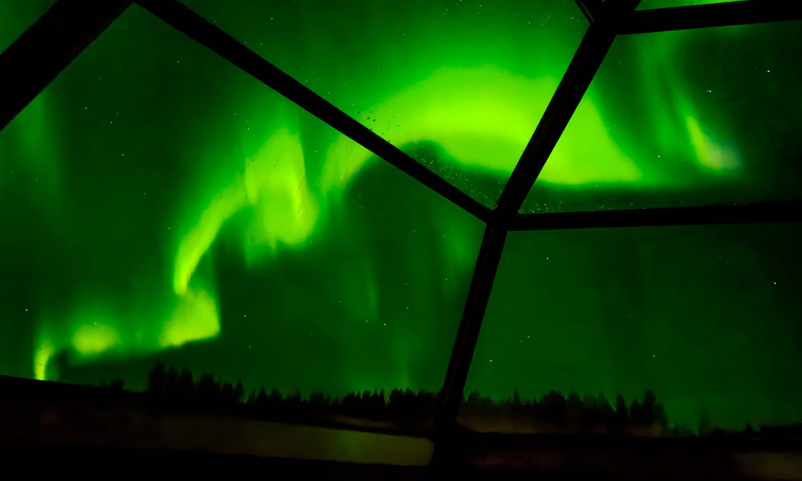 Northern lights behind windows of the glass igloo