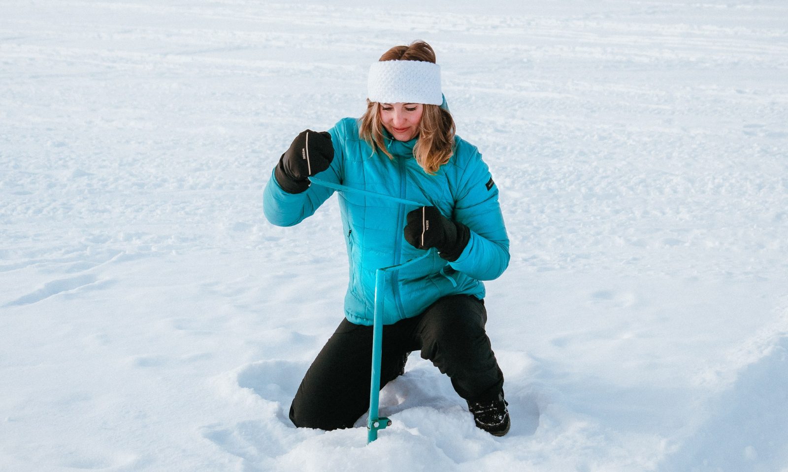 Nainen kairaa pilkkireikää