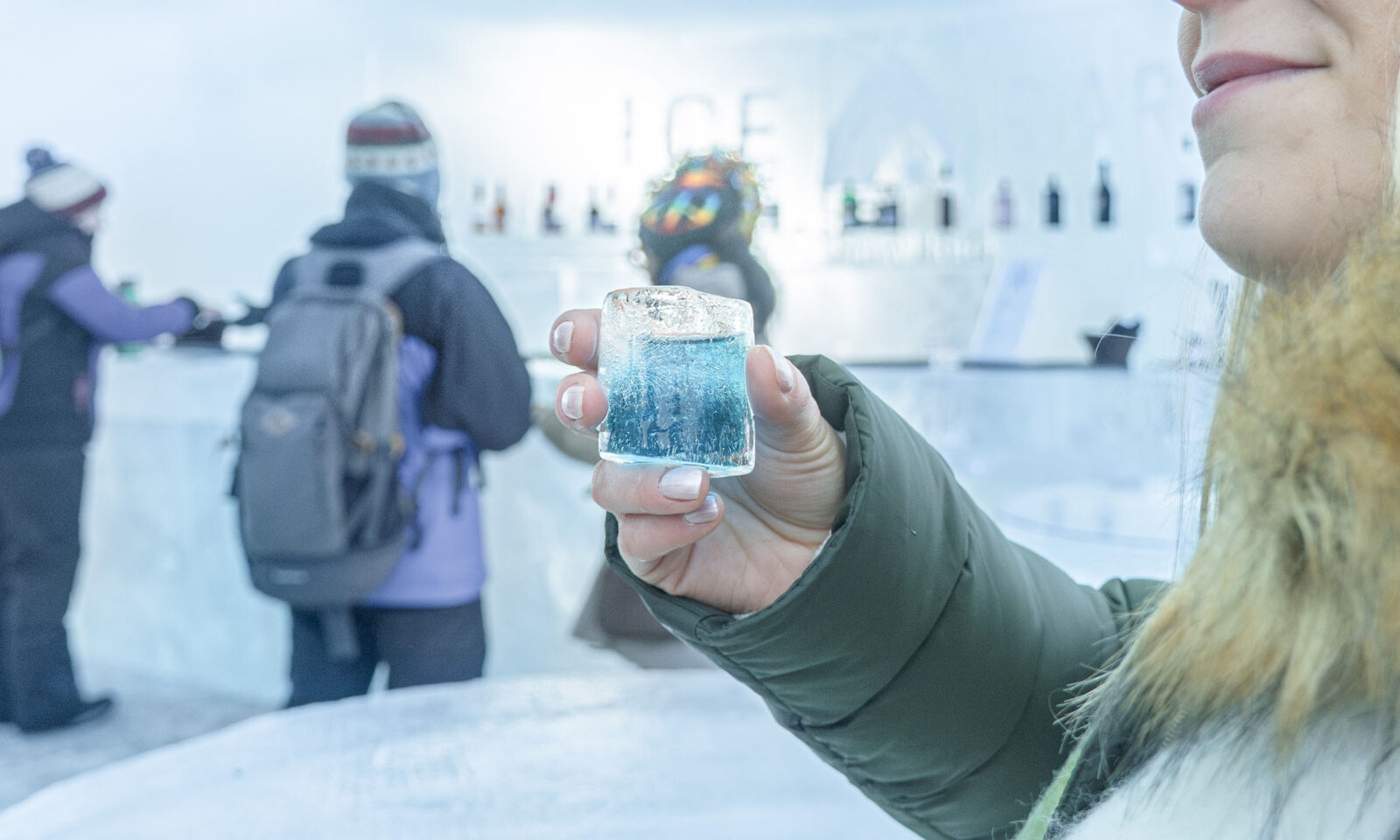 Visitor with an ice drink in hand, ice bar in the background