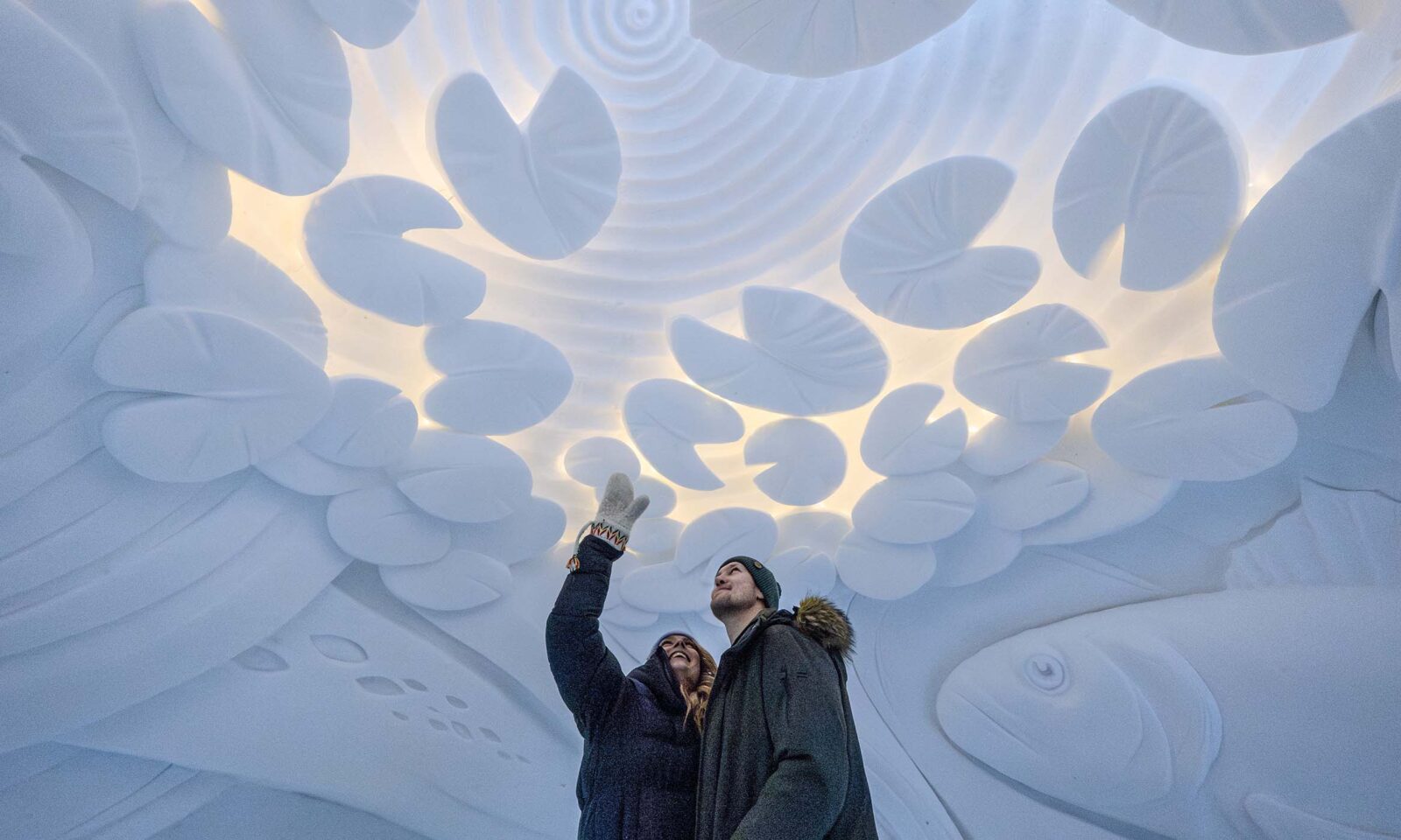 Two visitors admiring the snow art in guided tour of the snow hotel