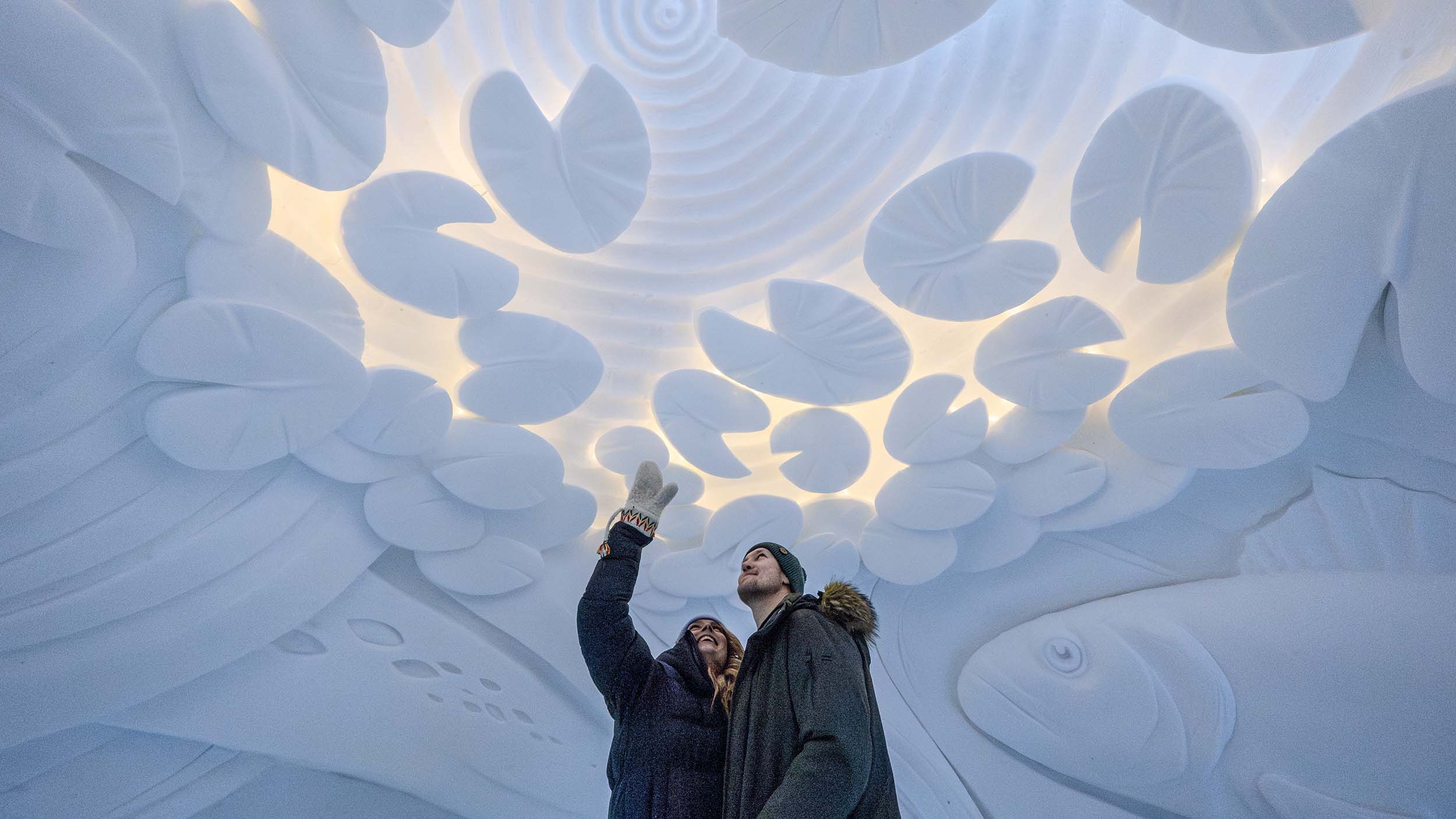 Two visitors admiring the snow art in guided tour of the snow hotel