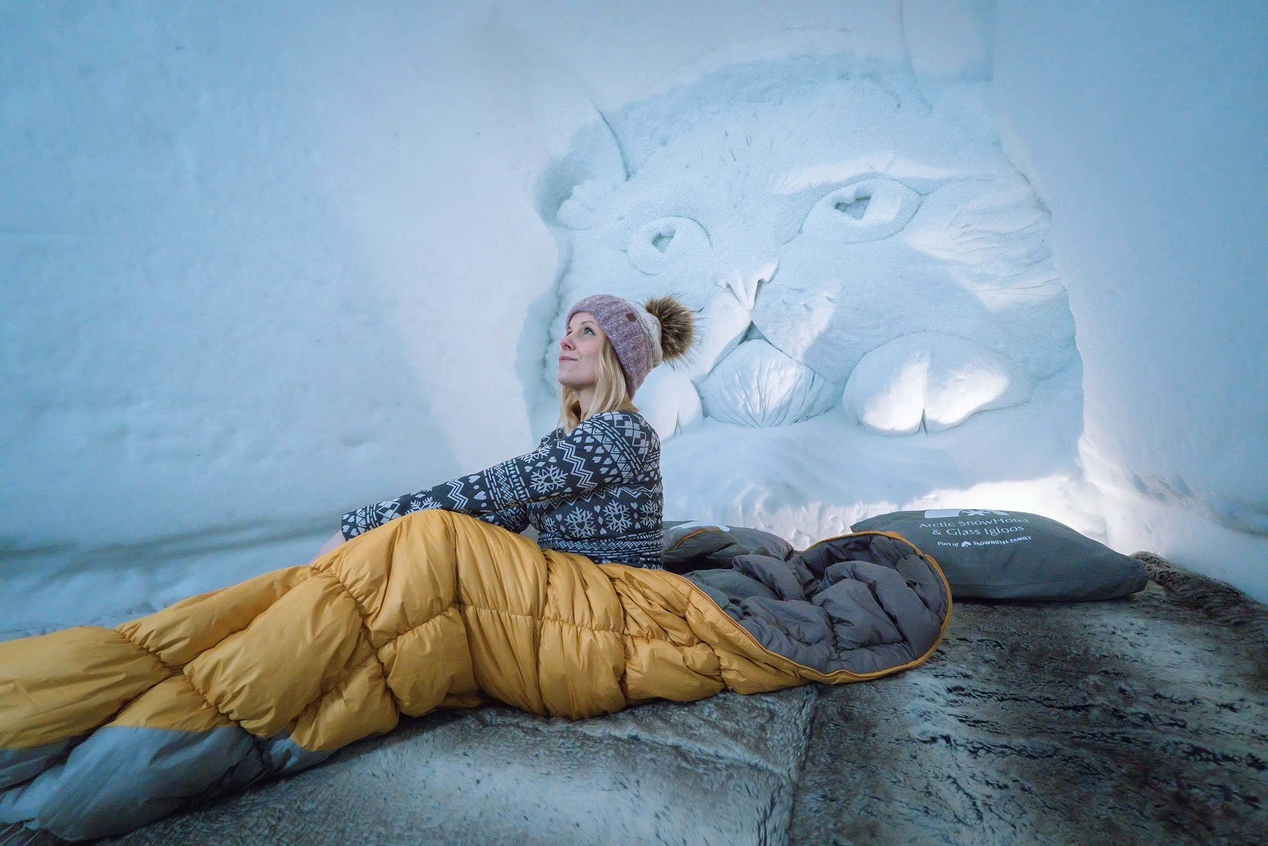 A woman in a sleeping bag in snow hotel superior room