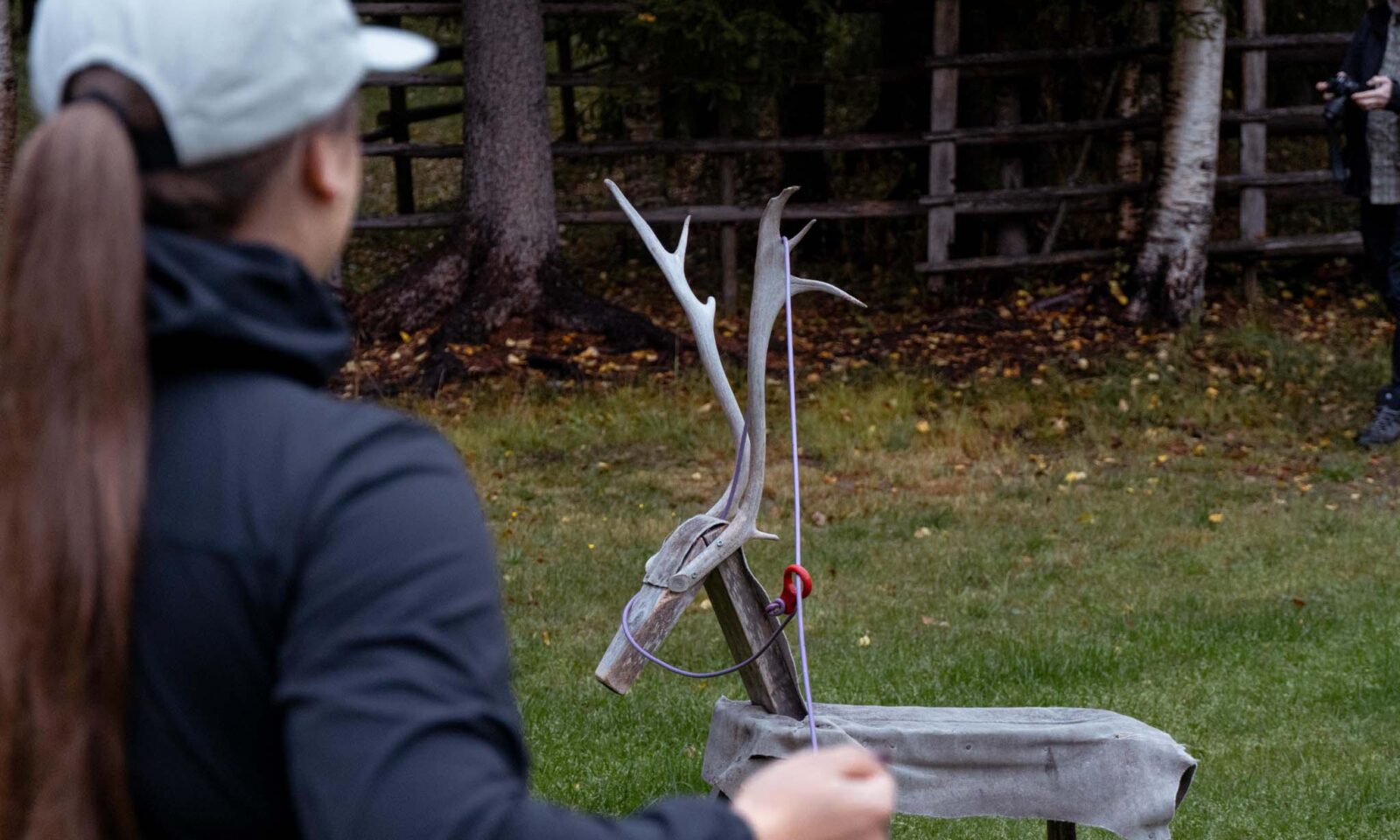 A visitor throws a suopunki at a wooden reindeer.