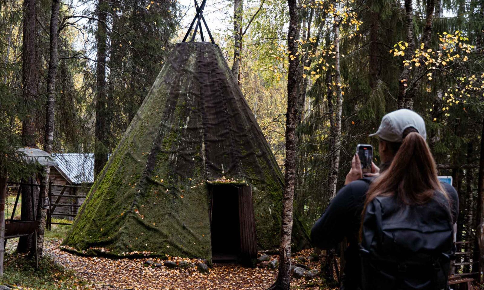 A visitor photographs an old Lappish hut.