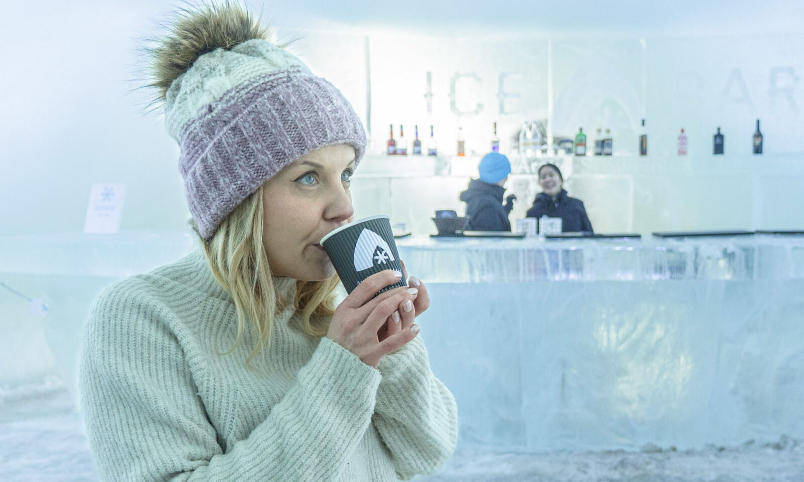 A woman drinking hot drink in the Ice bar.